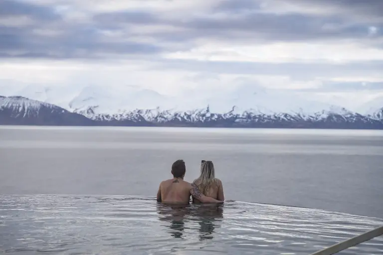 A young couple at the pool of GeoSea looking at the mountains