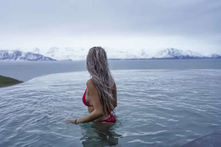 A woman is looking at the mountains from the GeoSea pool